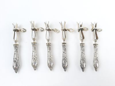 six cuillères en argent avec manche, posées sur un fond blanc