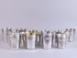 silver shot glasses lined up in a row on a white surface