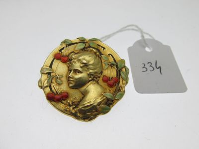 un gros plan d'une broche en or ornée de cerises
