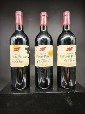 trois bouteilles de vin rouge sont alignées sur une étagère