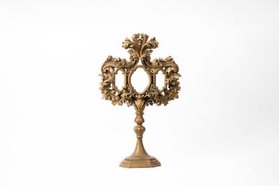 une horloge dorée posée sur un socle, sur fond blanc