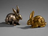 pair of bronze rabbit figurines on a grey background