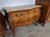 a marble top chest of drawers next to a wooden dresser