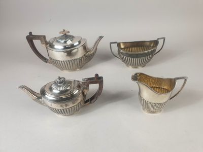 four pieces of silver tea and coffee set on a white surface