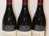trois bouteilles de vin rouge sont alignées sur une table