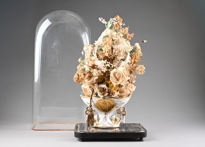 un vase contenant un bouquet de fleurs, recouvert d'une cloche en verre