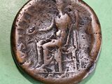 an old coin with a man sitting on a chair on a green surface