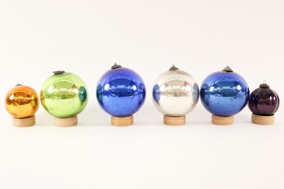 six different colored glass ornaments are lined up in a row