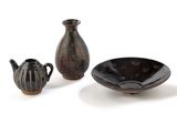 three pieces of pottery sitting on a white surface
