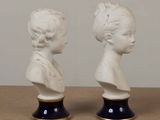 pair of white porcelain busts of a boy and a girl on black bases