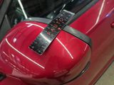 a close up of a red car with a ruler on the side mirror