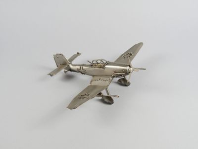 une maquette argentée d'un petit avion posée sur une surface blanche