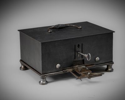 une vieille boîte en métal noir sur laquelle repose une clé