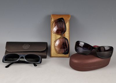 une paire de lunettes de soleil et un étui à lunettes posés sur une table à côté d'une autre paire de lunettes de soleil