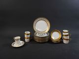 une image représentant un ensemble d'assiettes et de tasses dorées et blanches
