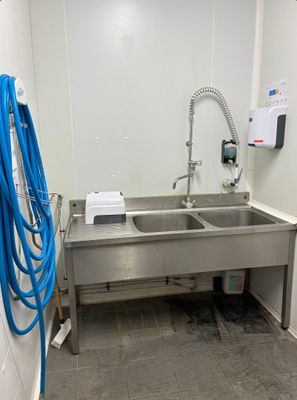 une photo d'une salle de bains avec un lavabo et un tuyau accroché au mur