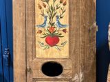 une grande armoire en bois ornée d'un tableau, à côté d'une pile d'autres objets