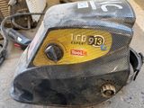 a close up of a welding machine on the ground in a garage