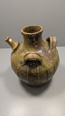 un vase marron posé sur une table, avec un mur blanc en arrière-plan