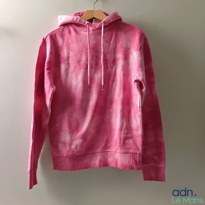 a pink hoodie hanging on a hanger against a white wall