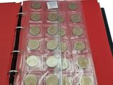 a red binder with a bunch of coins inside of it