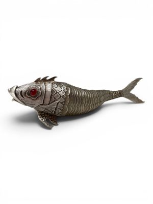 a silver fish figurine with red eyes on a white surface