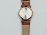 a close up of a watch on a white surface with a brown strap