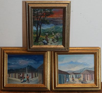 trois tableaux encadrés représentant une scène de village, posés sur une table en bois