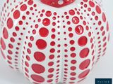 a red and white vase with polka dots on it