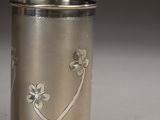 a silver cup with flowers on it sitting on a table