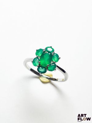 un gros plan d'une bague en pierre verte posée sur une surface blanche