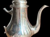 une théière en argent avec une anse, sur fond noir