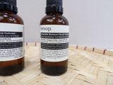 two bottles of liquid sitting on top of a wooden table