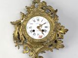 une horloge dorée sur un mur blanc, avec un fond blanc