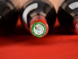 four bottles of wine are lined up on a red surface