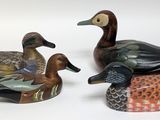 three ducks sitting on top of each other on a white surface