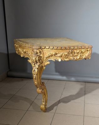 une table dorée avec un plateau en marbre, posée sur un sol carrelé
