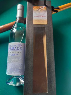 une bouteille d'alcool posée à côté d'un couteau sur une table de billard