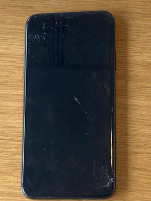 un iPhone à l'écran fissuré posé sur une table en bois