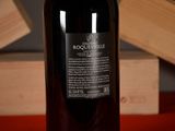 a bottle of wine sitting on a table with a wooden block in the background