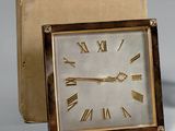 une petite horloge carrée avec des chiffres romains