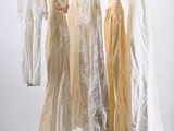 three dresses hanging on a clothes rack in a room