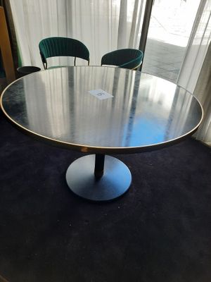 une table ronde avec deux chaises vertes devant une fenêtre
