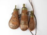 trois briquets anciens en laiton sur fond blanc, avec un cordon en cuir