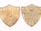 two gold colored metal shields with a bird and flowers on them