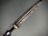 a close up of a knife on a table with a gray background