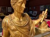 a gold statue of a man holding a clock in a room