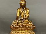 a gold statue of a person sitting on top of a table