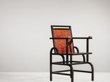 une image représentant une chaise noire sur laquelle est posé un coussin rouge