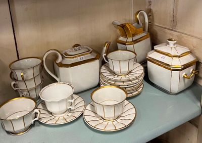 beaucoup d'assiettes et de tasses blanches et dorées sur une étagère